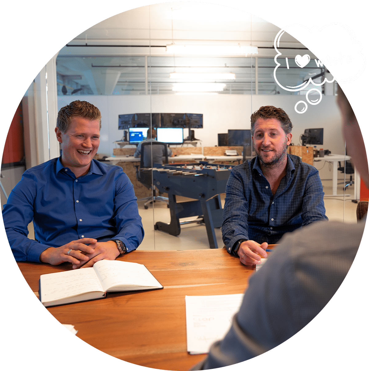 Twee mannen in een zakelijke bijeenkomst in een vergaderruimte, lachend en met een notitieboekje op tafel